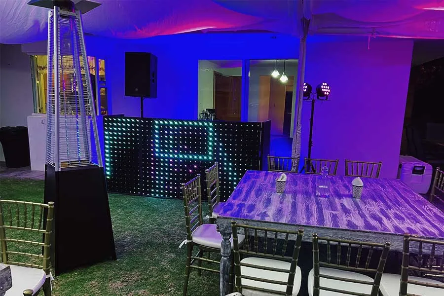DJ con cabina LED para evento nocturno al aire libre con carpa y mobiliario elegante
