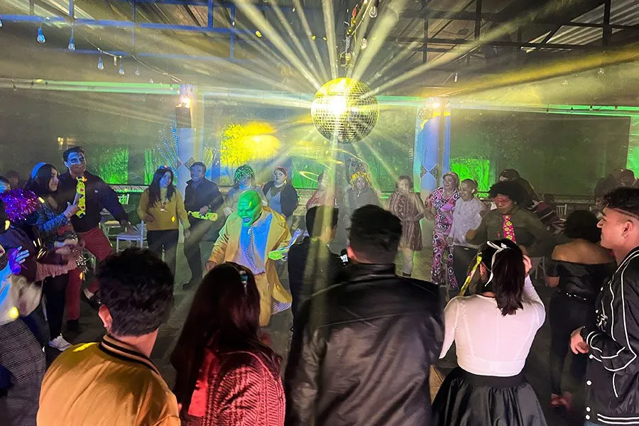 DJ para fiesta retro con disfraces, bola disco y pista llena de invitados